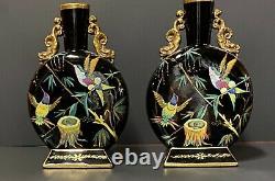 A pair of opaque, flat and round, gilded and painted black opaline glass vases