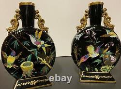 A pair of opaque, flat and round, gilded and painted black opaline glass vases